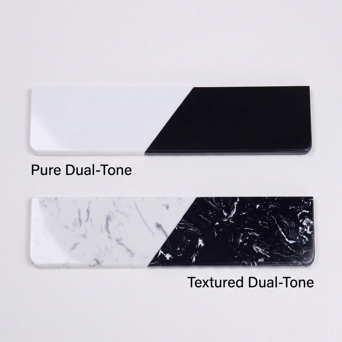 A comparison shot of two quartz stone wrist rests stacked vertically. The top one is labeled "Pure Dual-Tone" featuring solid black and white sections. The bottom one is labeled "Textured Dual-Tone" featuring black and white sections with marble patterns.
