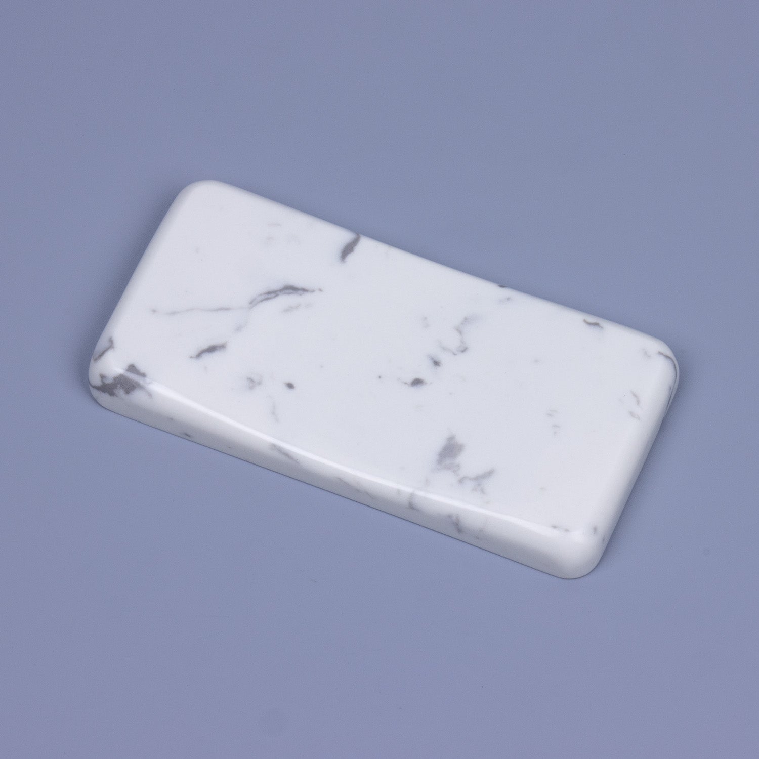 Angled side view of an ergonomic white marble quartz mouse wrist rest with beautiful grey veining and polished rounded corners
